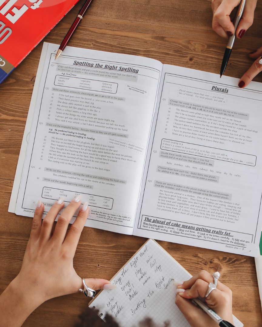 A tutor and student working through English and science workbooks together at a table